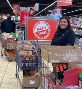 Two Interns standing in line at aldi with food for food drive